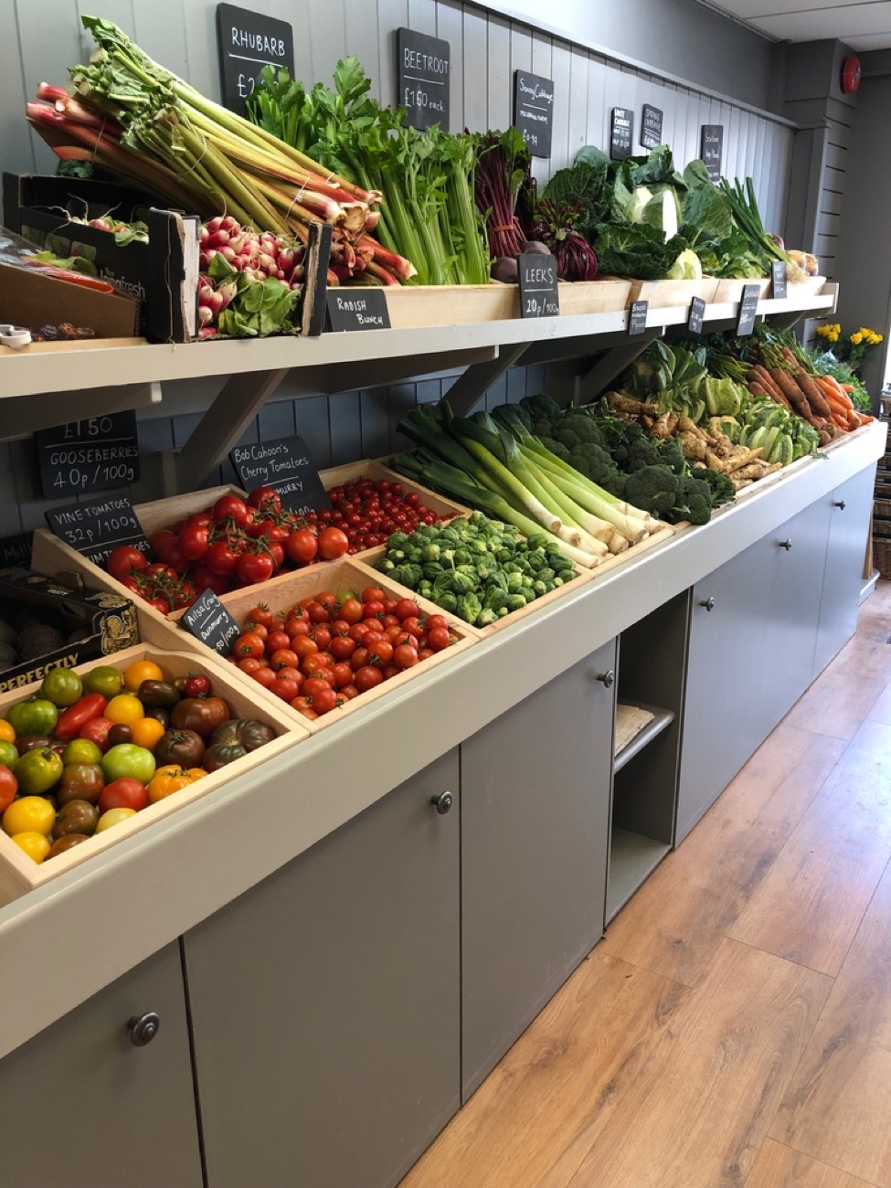 The long produce counter running down the shop, tomatoes and rhubarb in the foreground