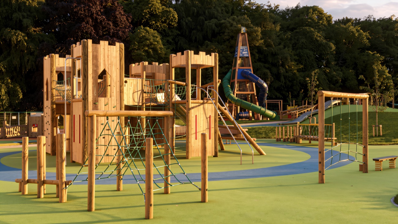 A large timber castle-style climbing structure with a blue tube slide at Mo Mowlam Play Park