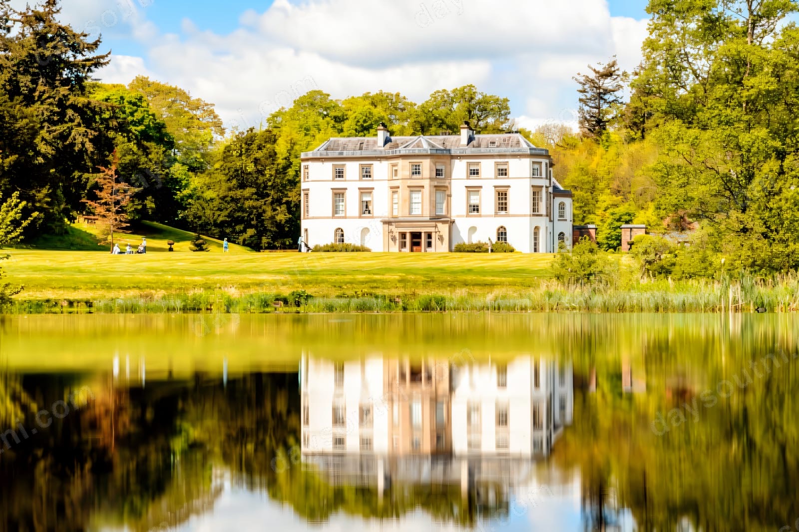 Montalto's white mansion reflected in the lake, framed by lawns and woodland