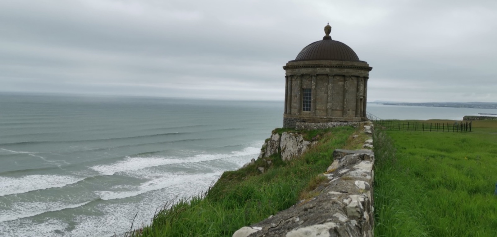 Mussenden Temple on the cliff edge above the strand under a moody sky