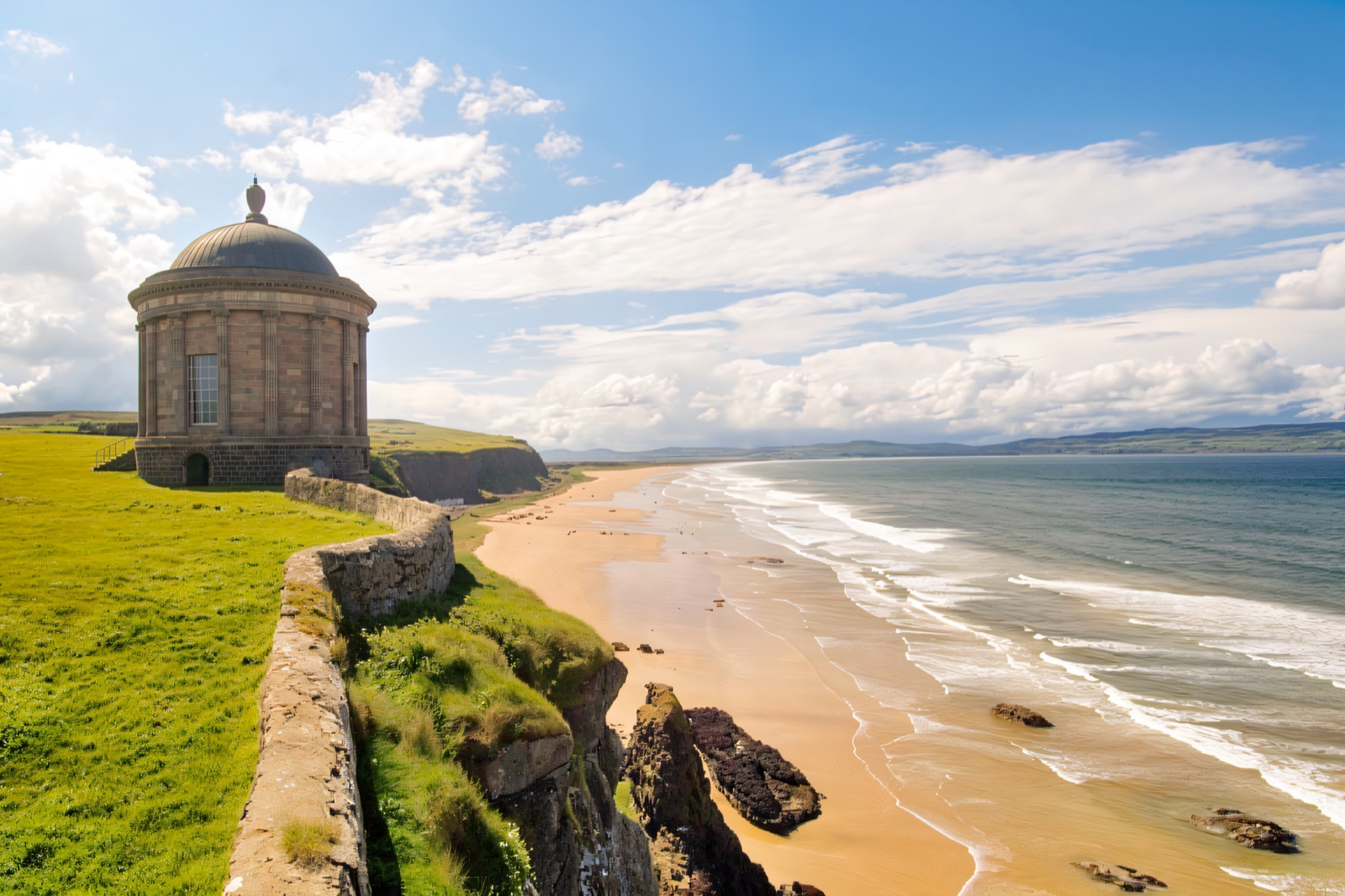 The round domed Mussenden Temple standing against a blue sky above the sea