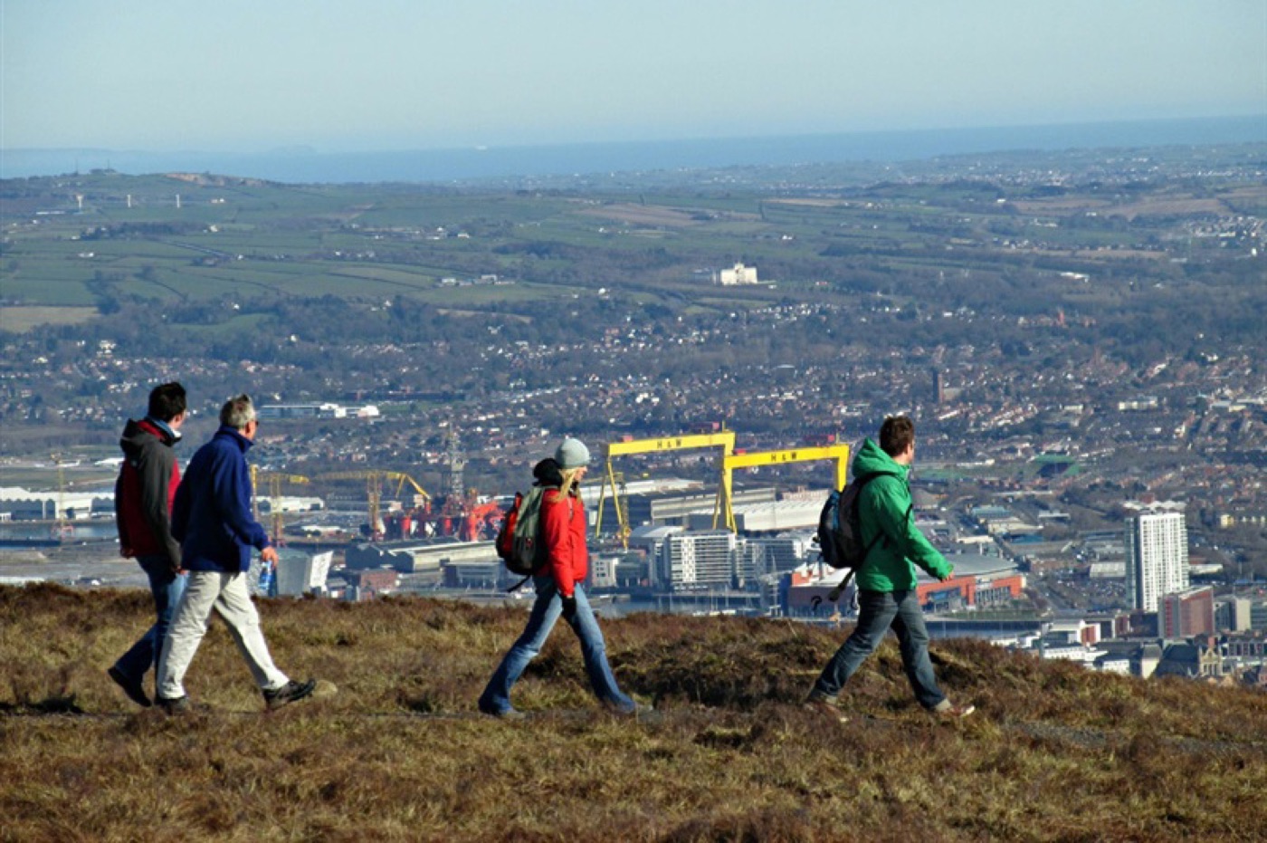 Walkers on the ridge at Divis with Belfast and the shipyard cranes below