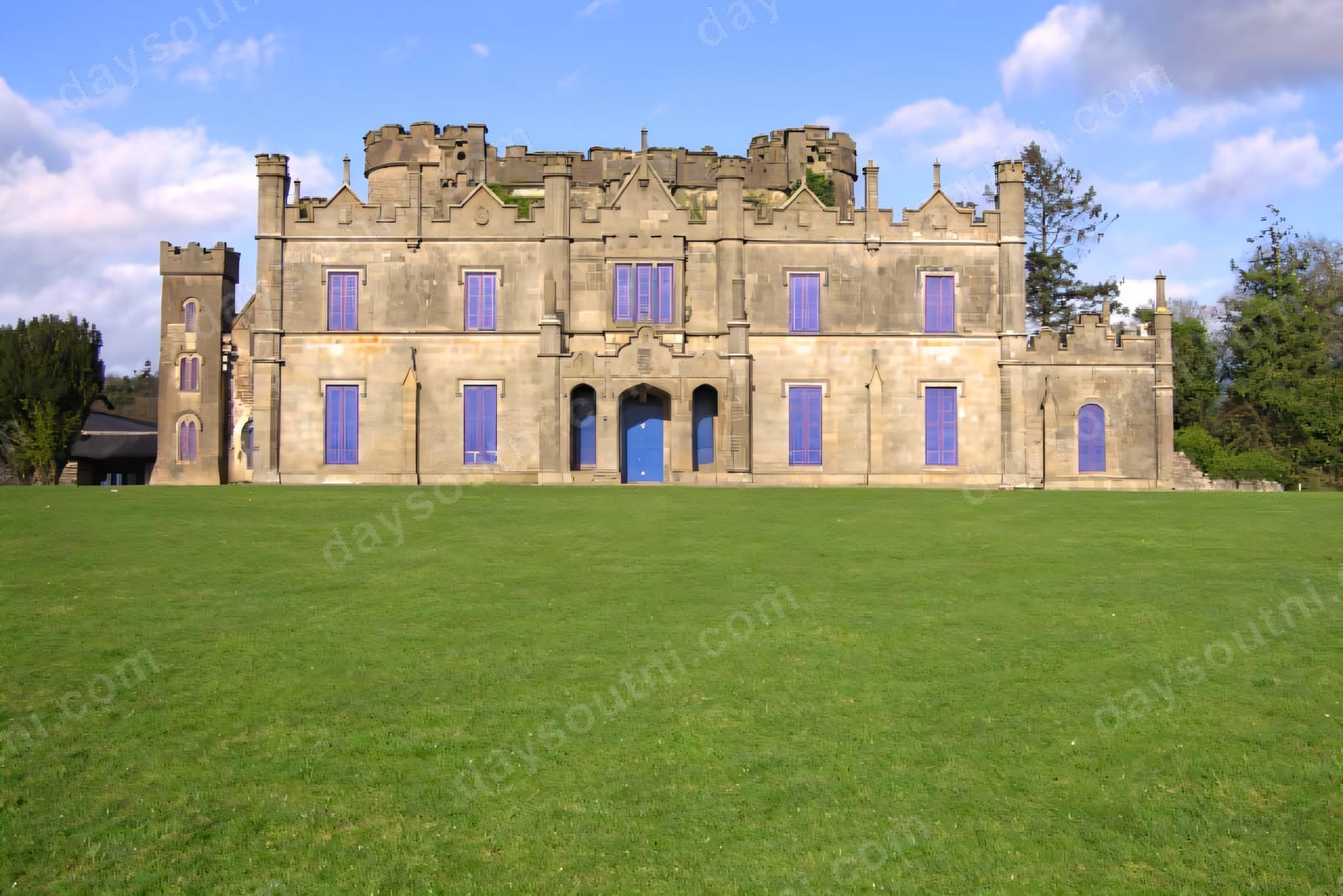 The grey Gothic-revival front of Necarne Castle, its battlements and windows above a wide green lawn