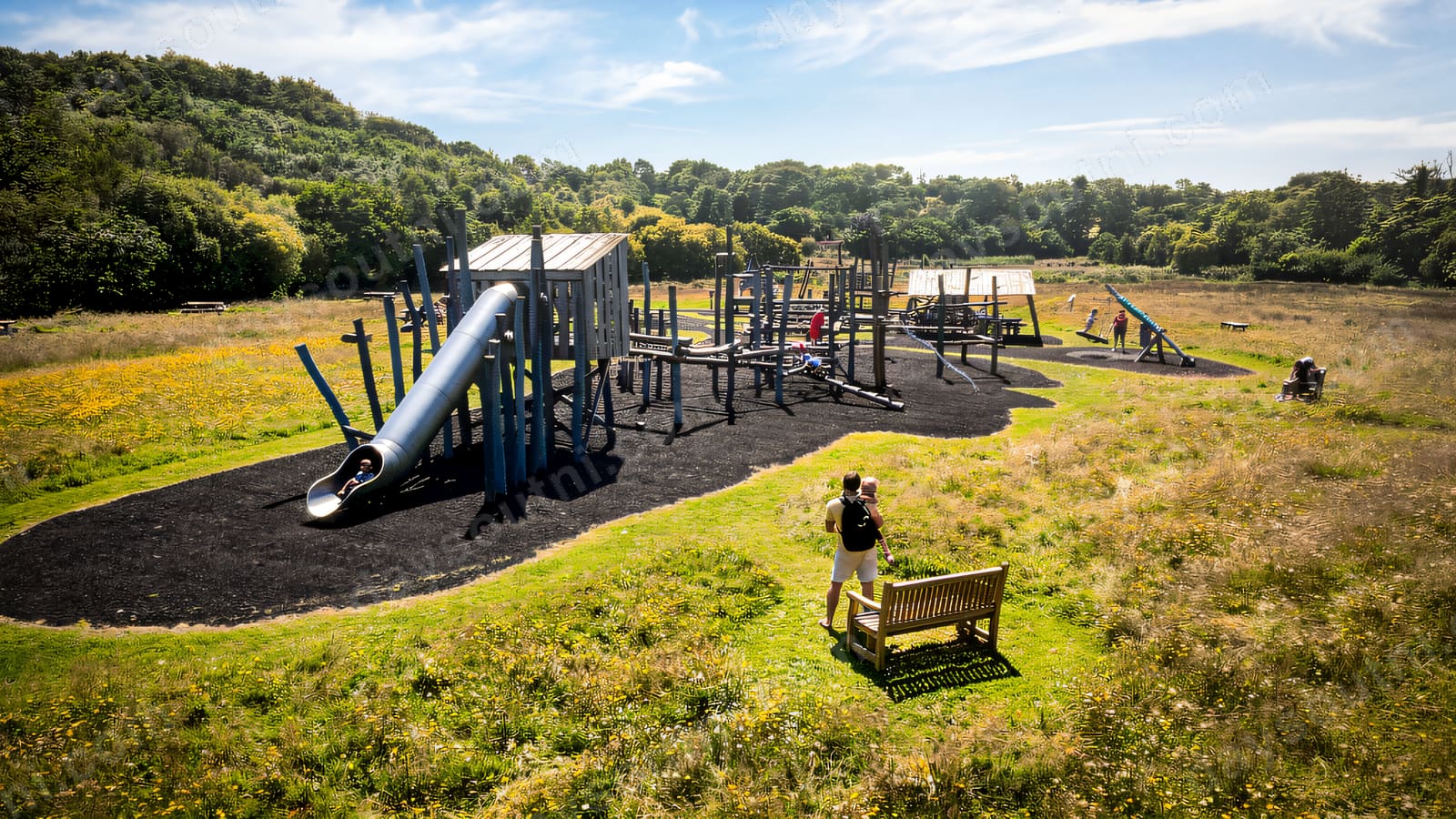 Children on the big slide and climbing towers of the adventure playground.