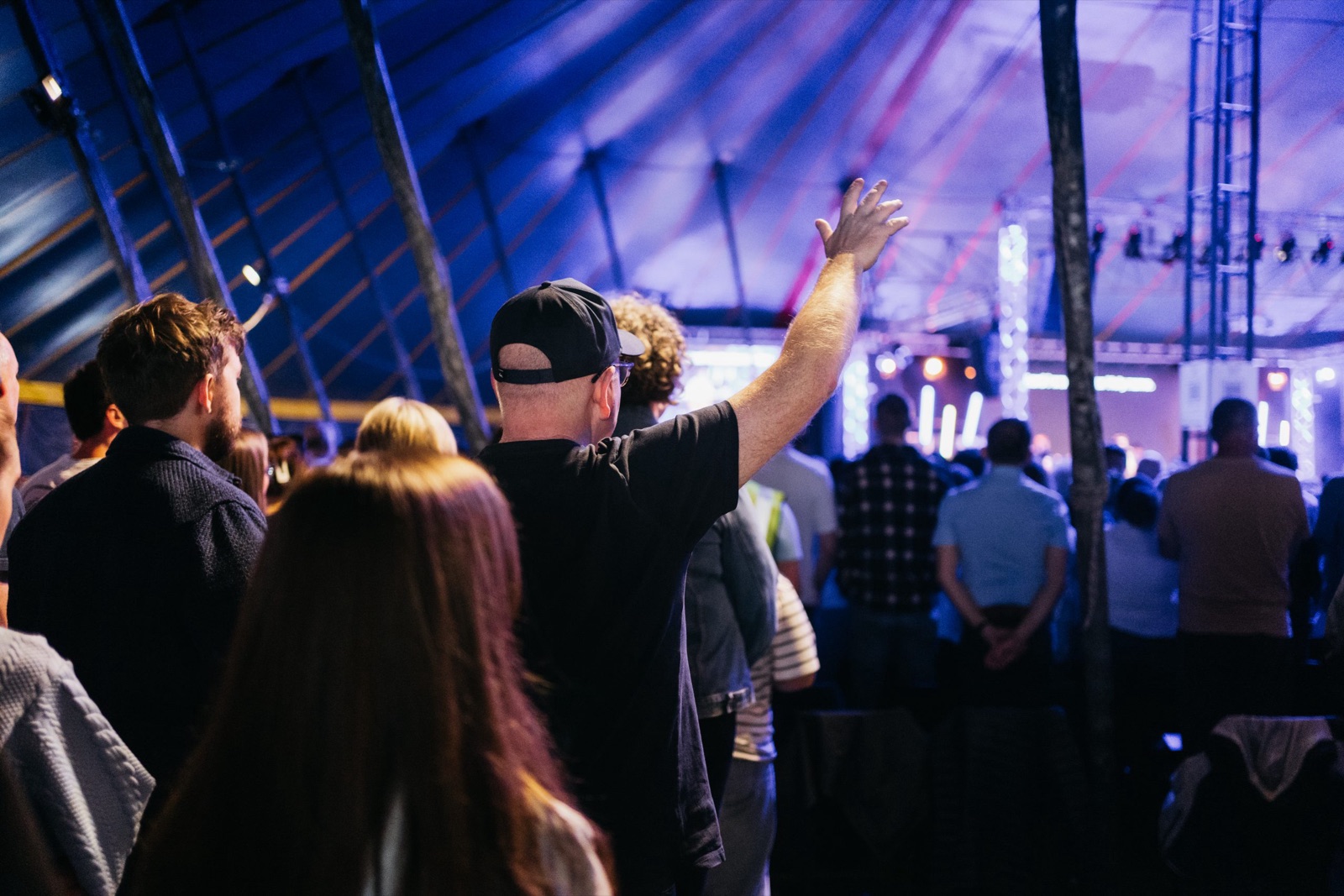 Worshippers in the main-stage tent at the New Horizon festival, one with a hand raised, facing the stage