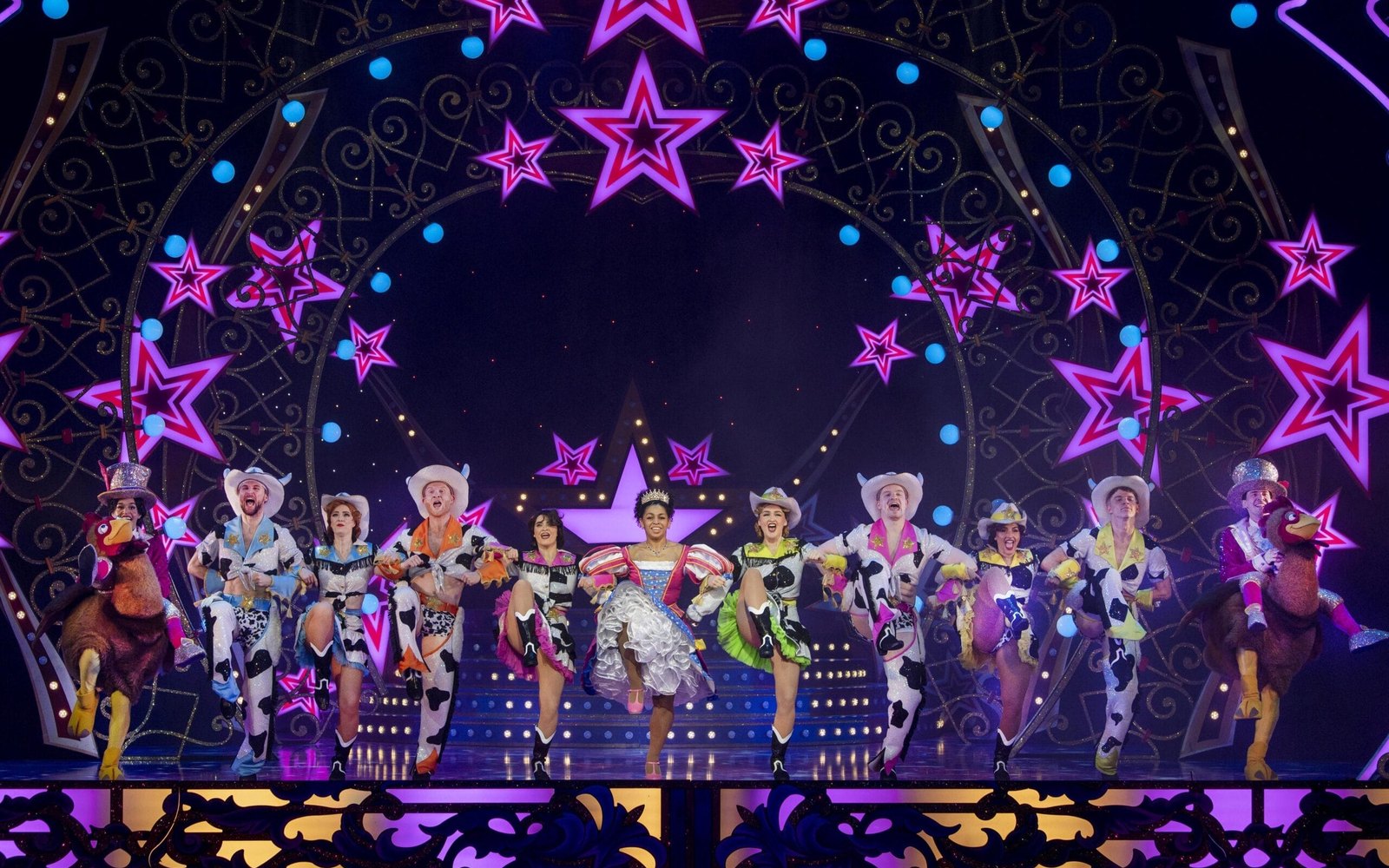A colourful pantomime cast on a brightly lit stage