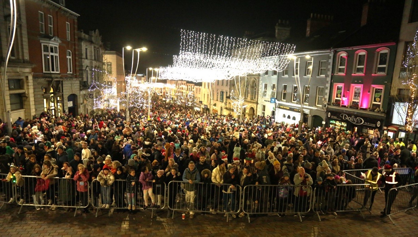 A crowd under a canopy of Christmas lights on a town centre street in Omagh
