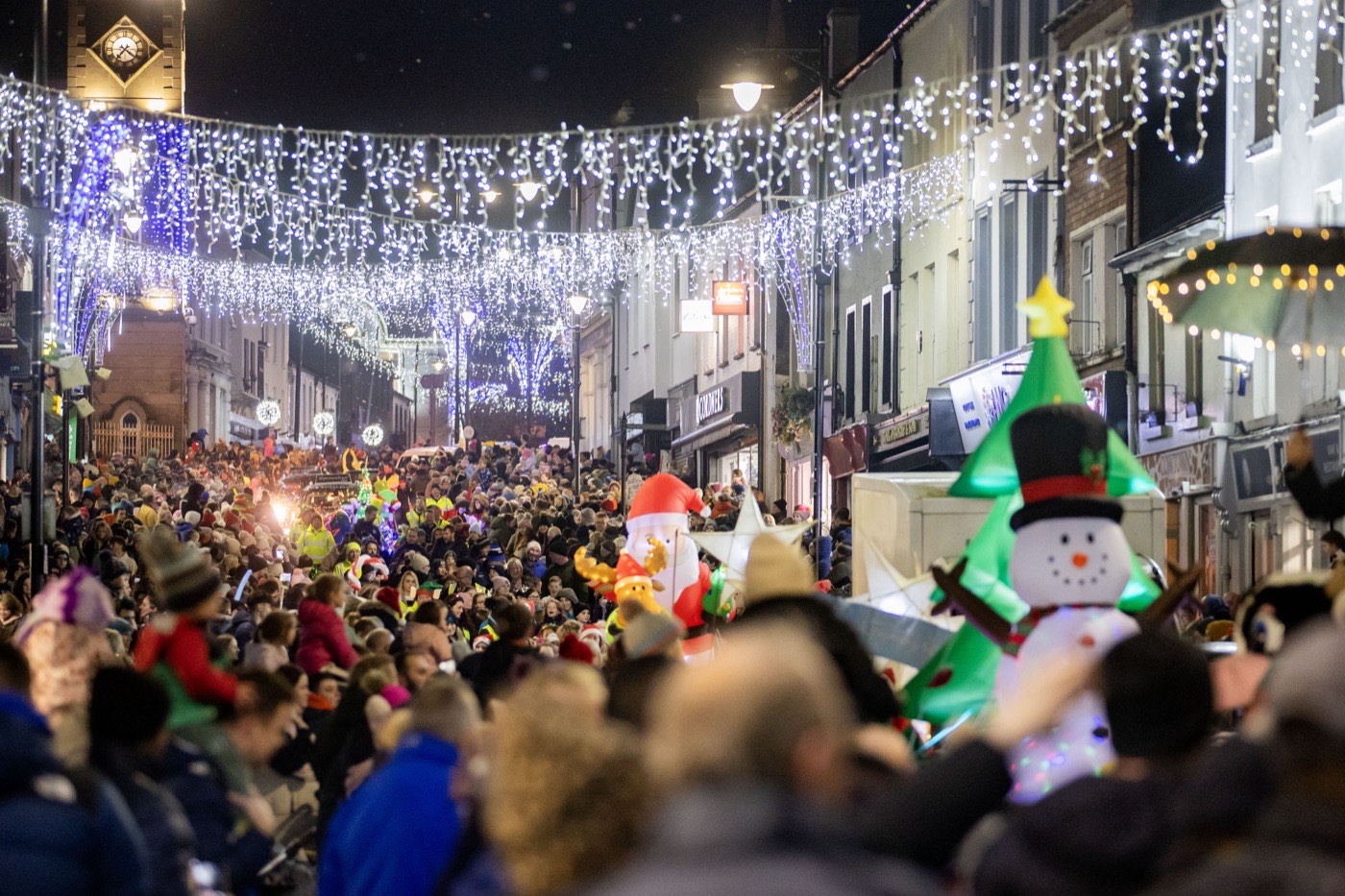A packed crowd under Christmas lights at a town centre switch-on