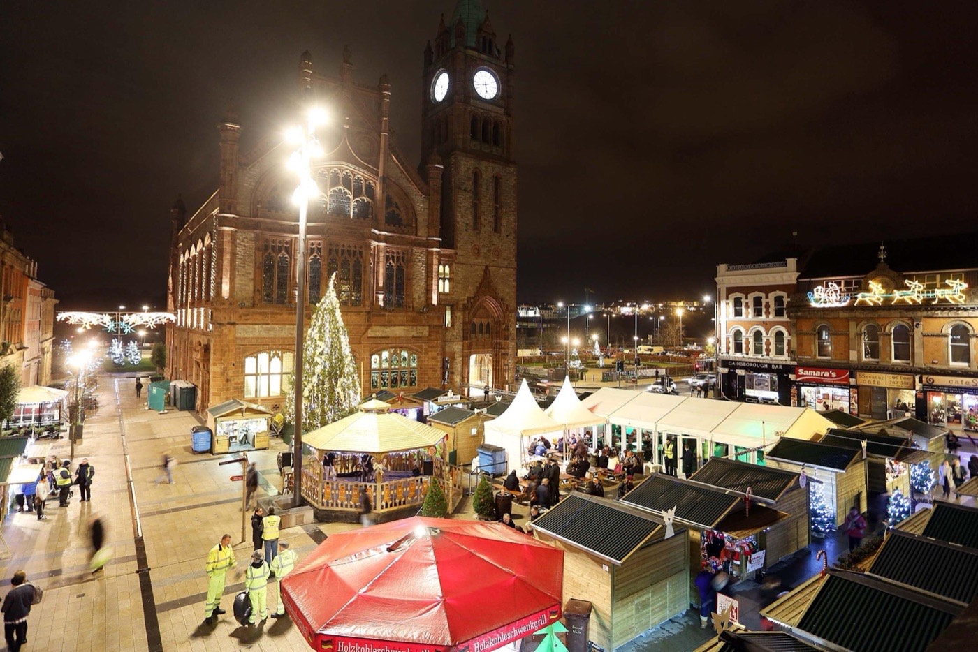 The Guildhall in Derry lit up behind Christmas market stalls