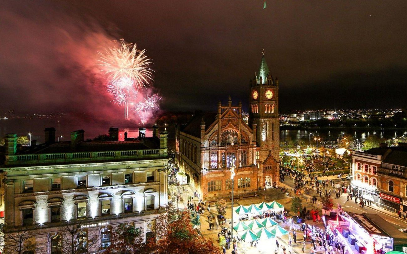 Costumed crowds and fireworks at the Derry Halloween parade at night