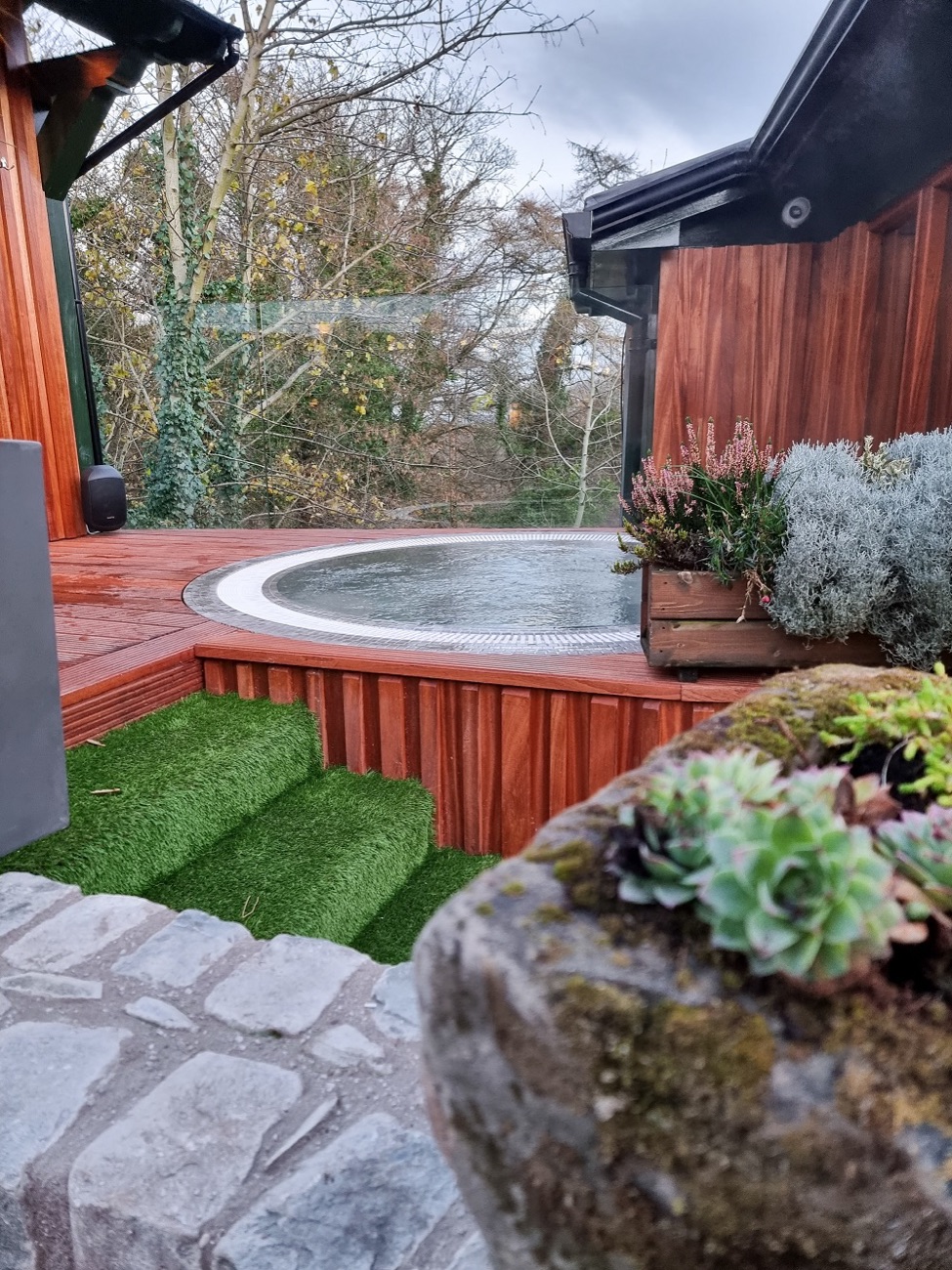 A round outdoor hot tub in a cedar surround, looking out over the bare winter trees.