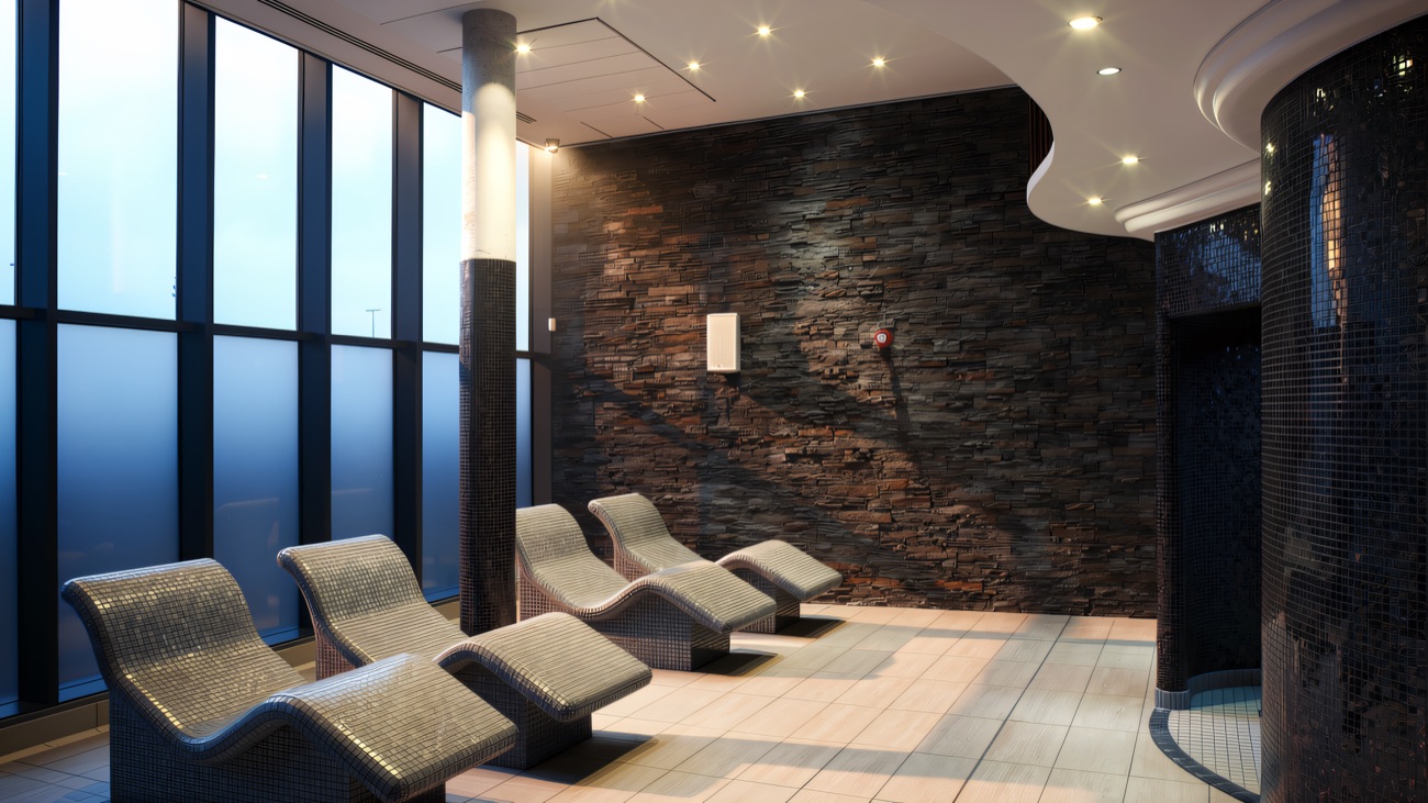 Heated relaxation loungers set along a wall of blue glass