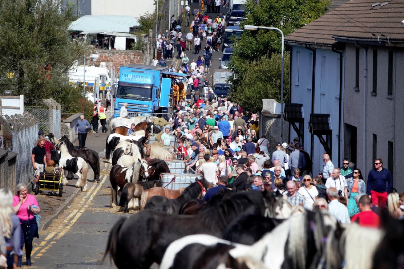 Piebald horses tethered along a Ballycastle street at the traditional Ould Lammas Fair horse fair, with crowds trading