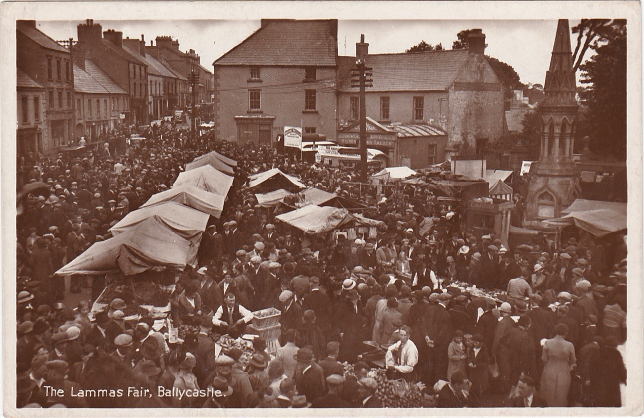 A vintage sepia photograph of the Lammas Fair in Ballycastle from the early twentieth century, crowds around canvas stalls