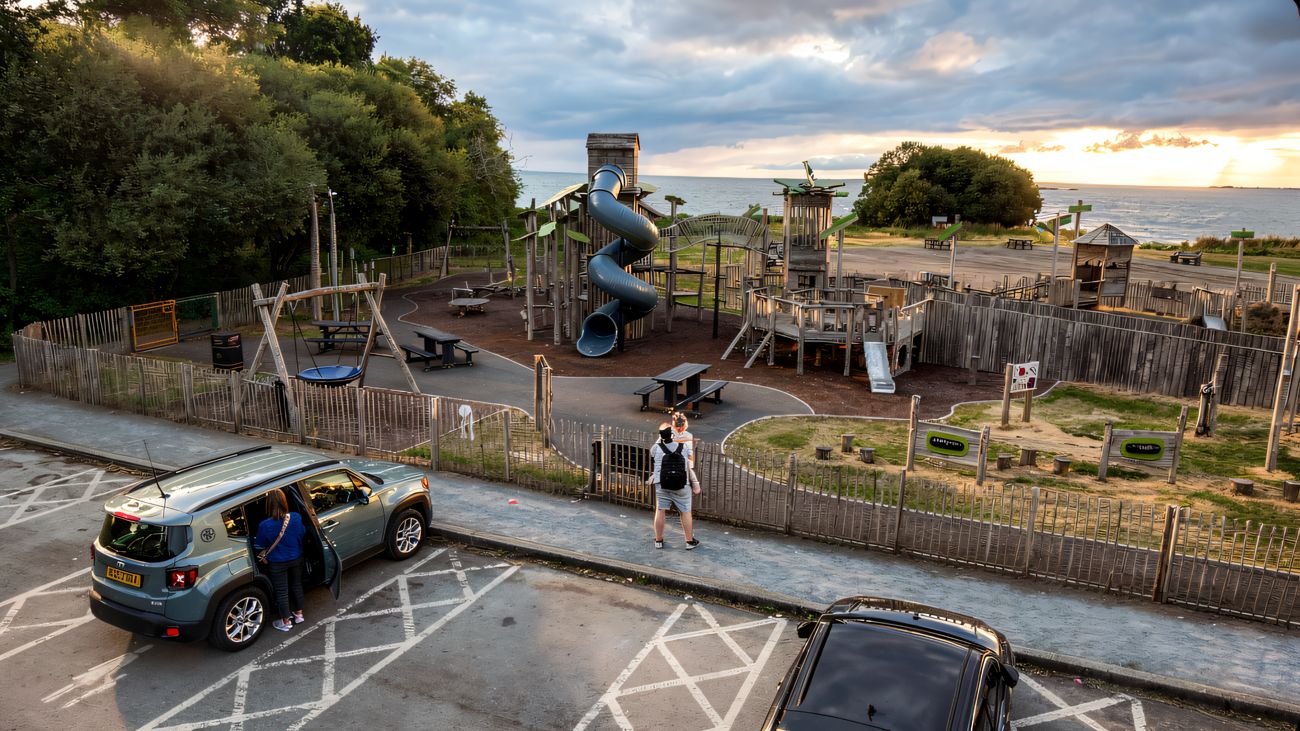 The Oxford Island play park from above at sunset, with the timber towers, palisade fence and car park