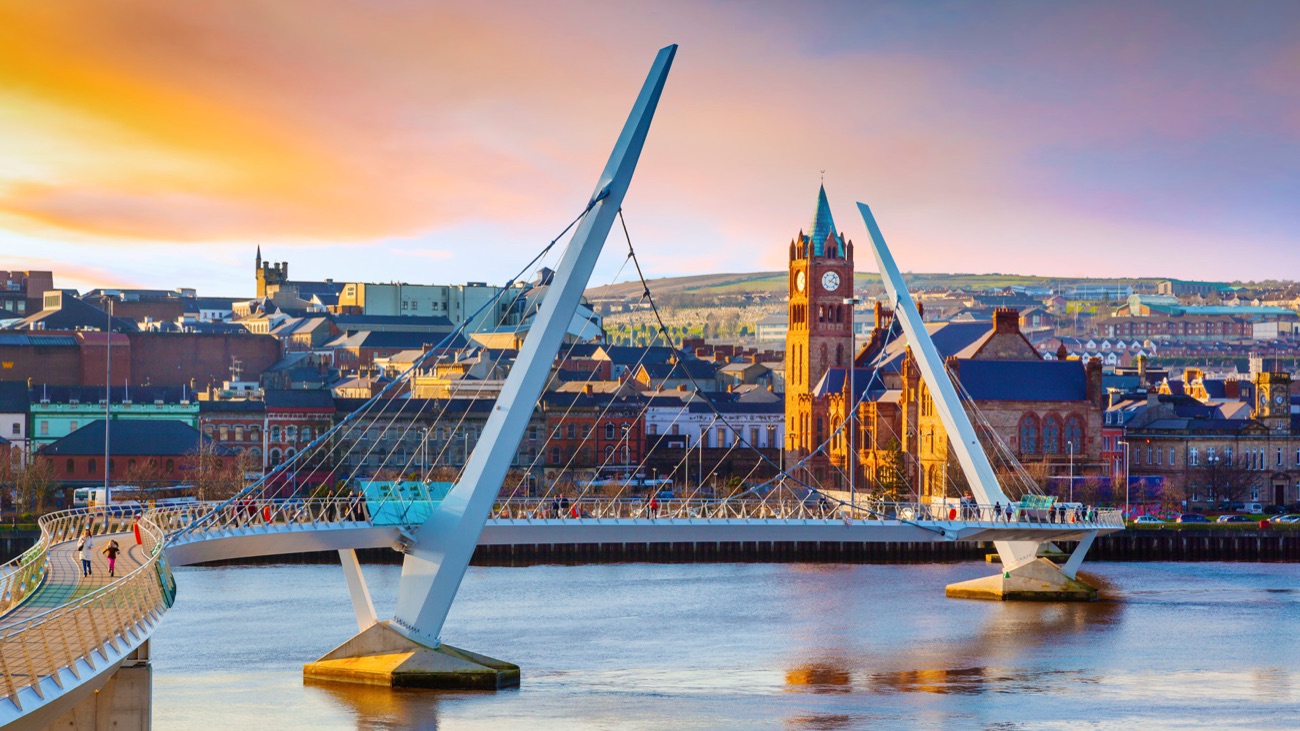 The Peace Bridge in warm sunset light sweeping over the Foyle with the Guildhall and city buildings behind