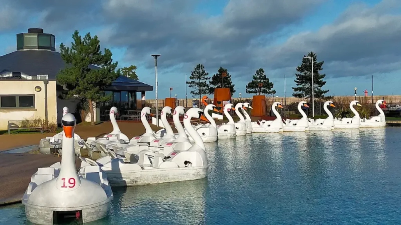 The white swan pedal boats lined up at the dockside under a dramatic Bangor sky