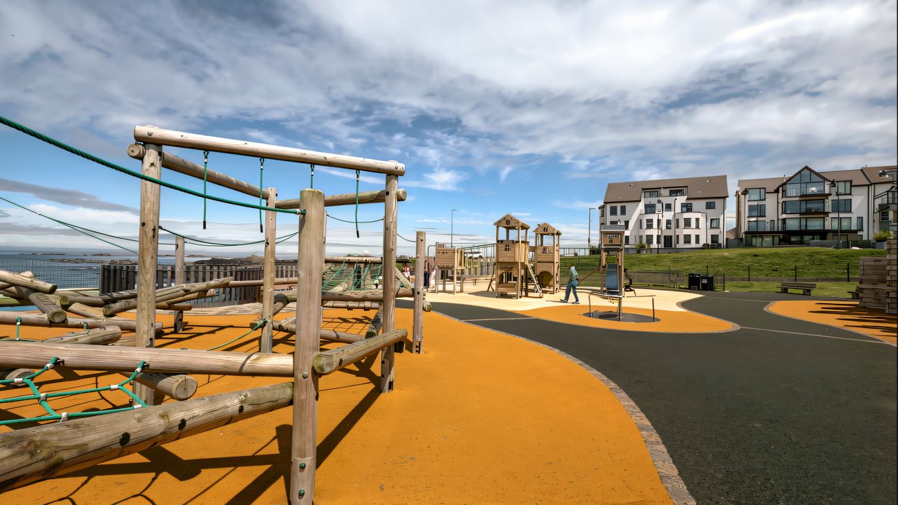 An aerial view of Portrush Recreation Grounds play park at sunset with the headland and sea beyond