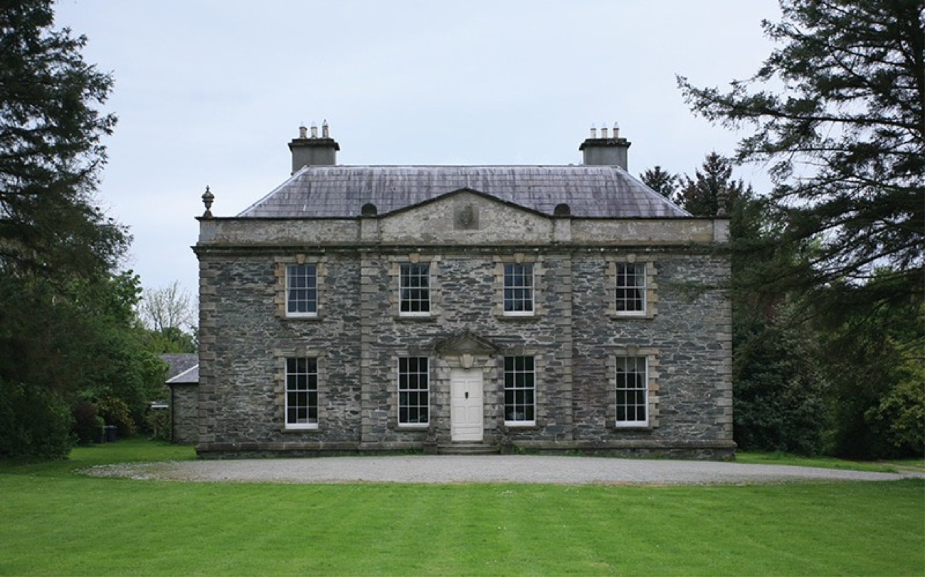 The symmetrical Georgian front elevation of Prehen House with its white door and wide green lawn
