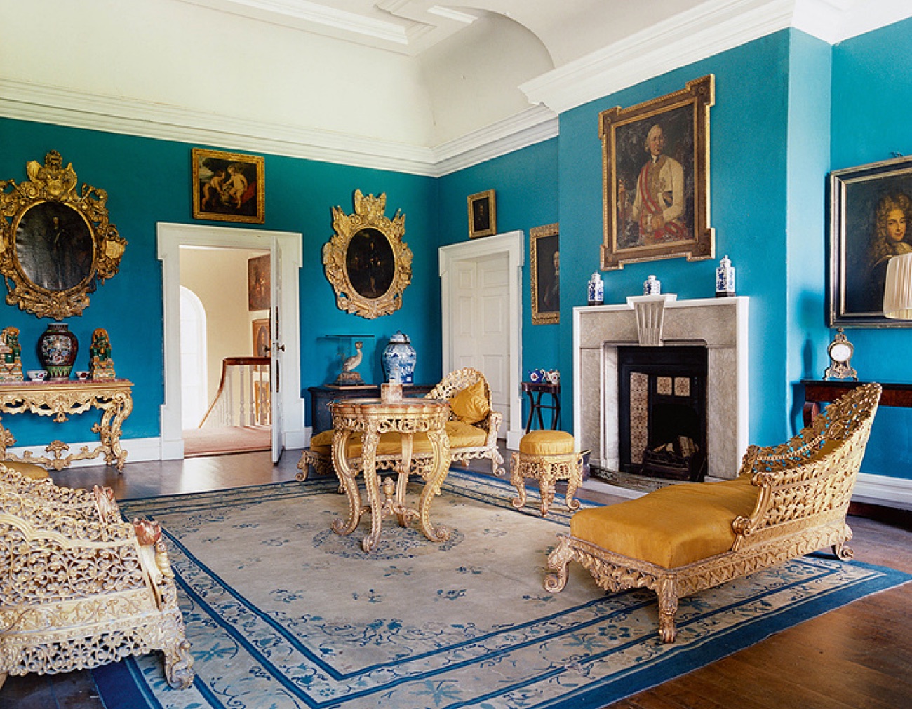 A grand teal-blue drawing room inside Prehen House with gilt furniture, portraits and a marble fireplace