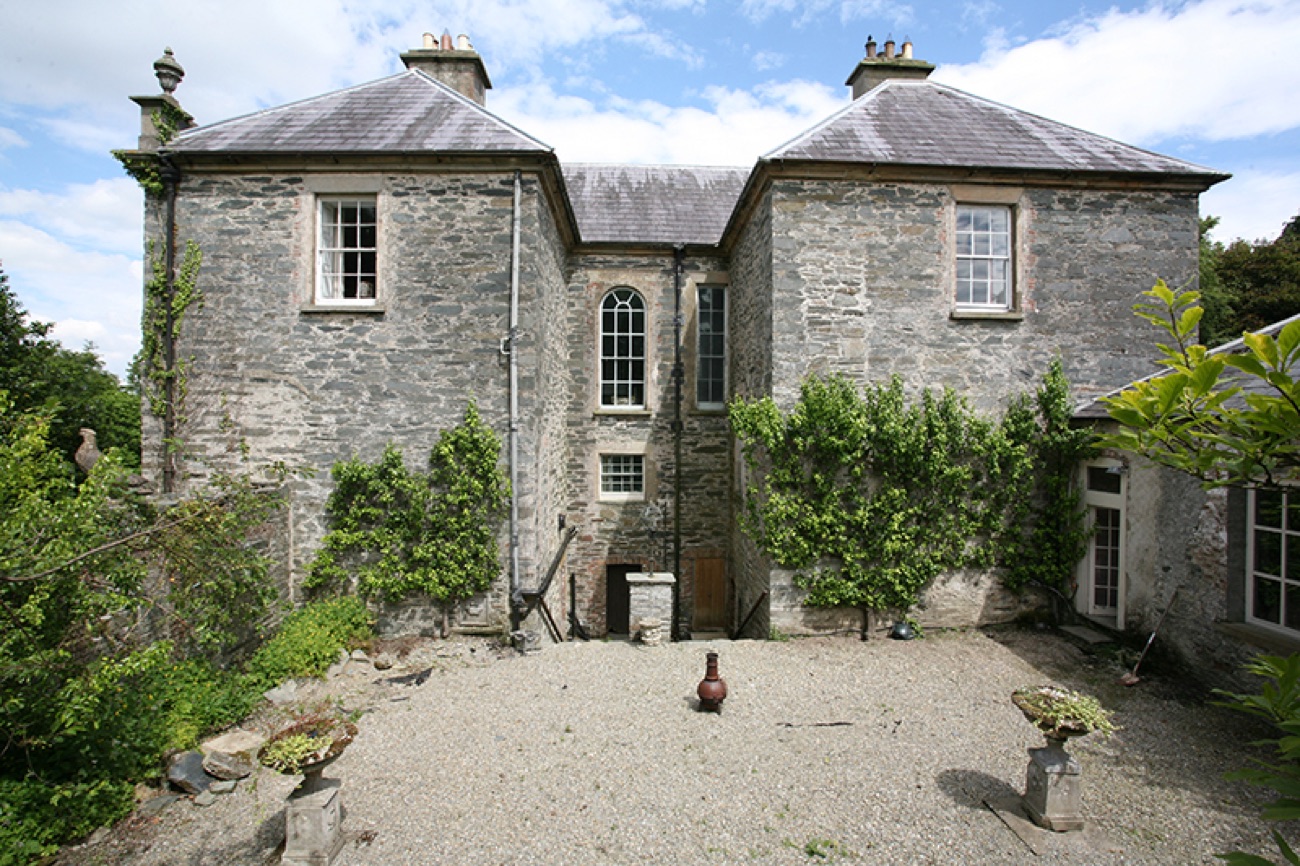 The rear courtyard of Prehen House with its tall arched stair window and gravel yard
