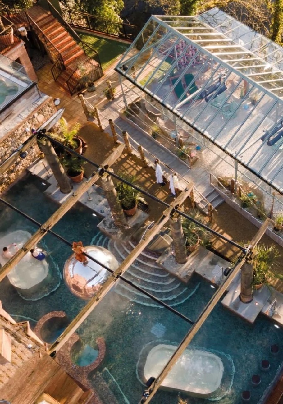 A view down over the lakeside spa: hot tubs, Roman baths and stone columns.