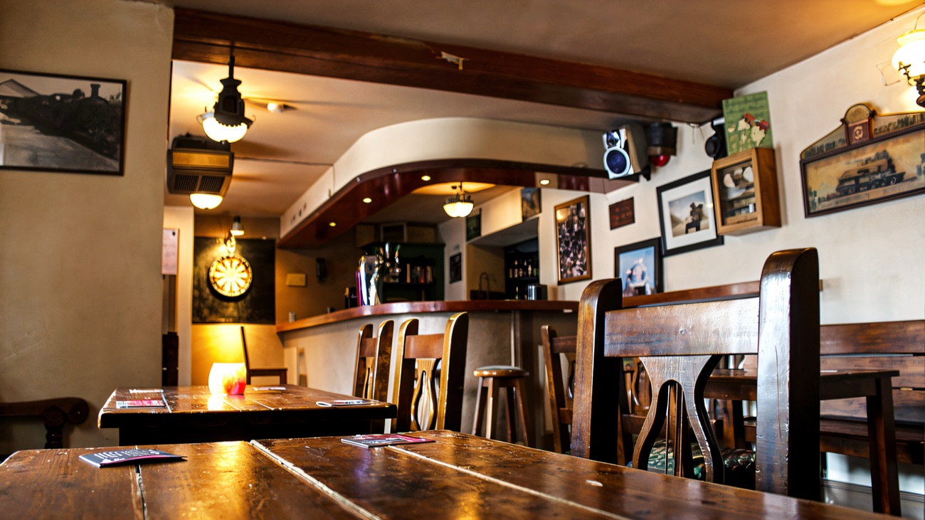The quiet front room, with old railway photographs on the walls and a dartboard in the corner