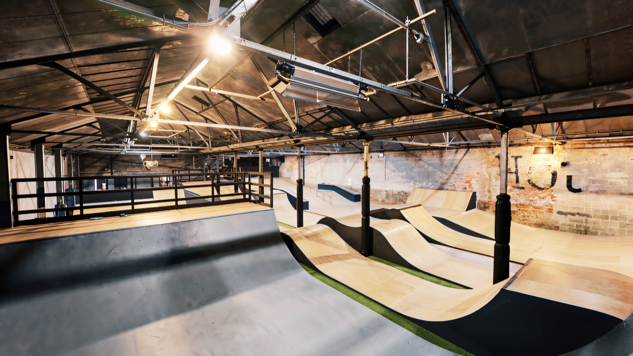 The empty indoor hall with its wooden rollers, banks and quarter pipes under the old brick walls