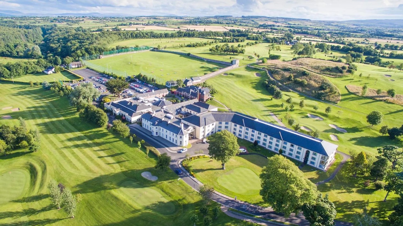 The resort seen from the air, wrapped in green golf-course parkland with the hills beyond.