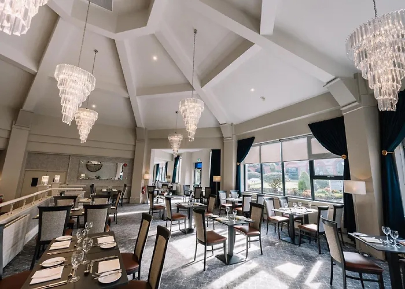 A bright resort dining room with tall ceilings and chandeliers.