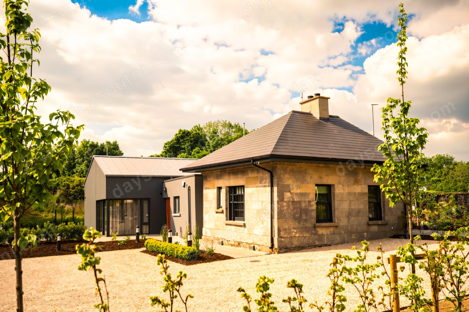 A stone lodge and modern glazed extension in the resort grounds on a bright day.