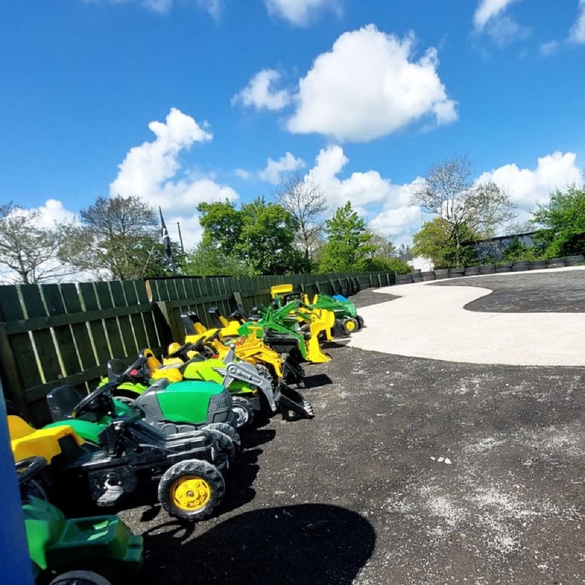 A row of ride-on toy tractors in the play yard