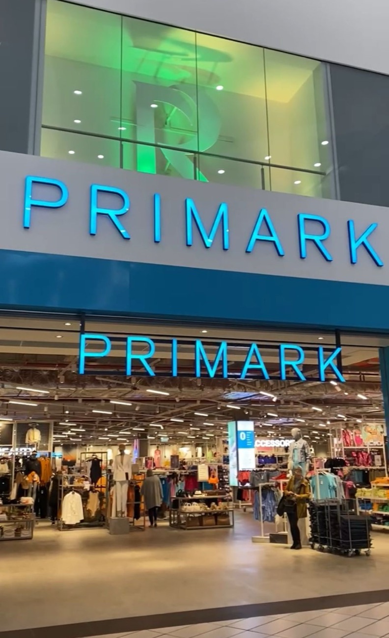 The blue-lit Primark storefront inside the mall at Rushmere Shopping Centre, with the shop floor glowing beyond the entrance