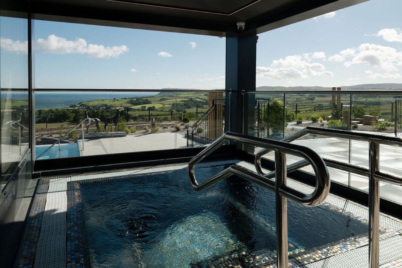 An outdoor bubbling vitality tub with an open view over the coastline and glens.