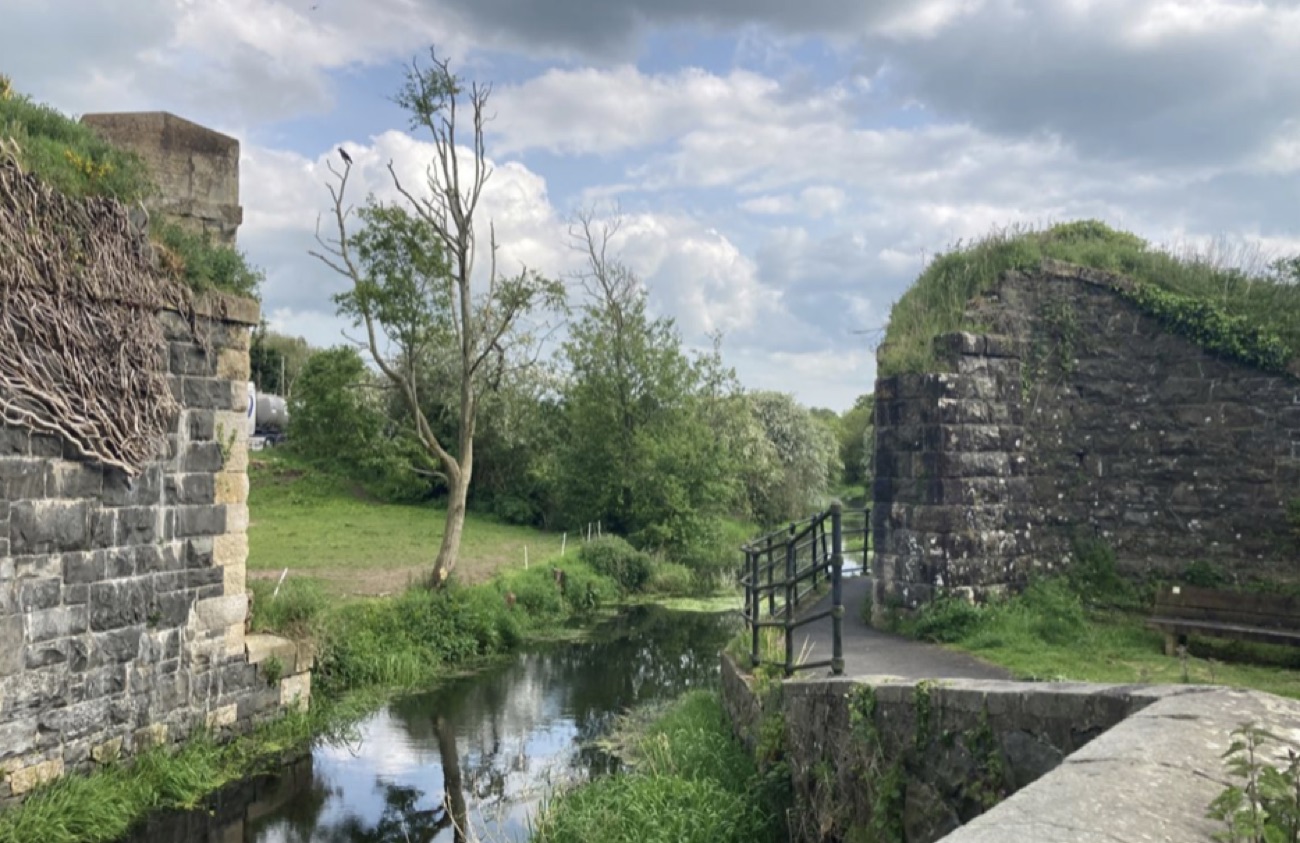 An old stone lock chamber on the Newry Canal with a footbridge and green banks