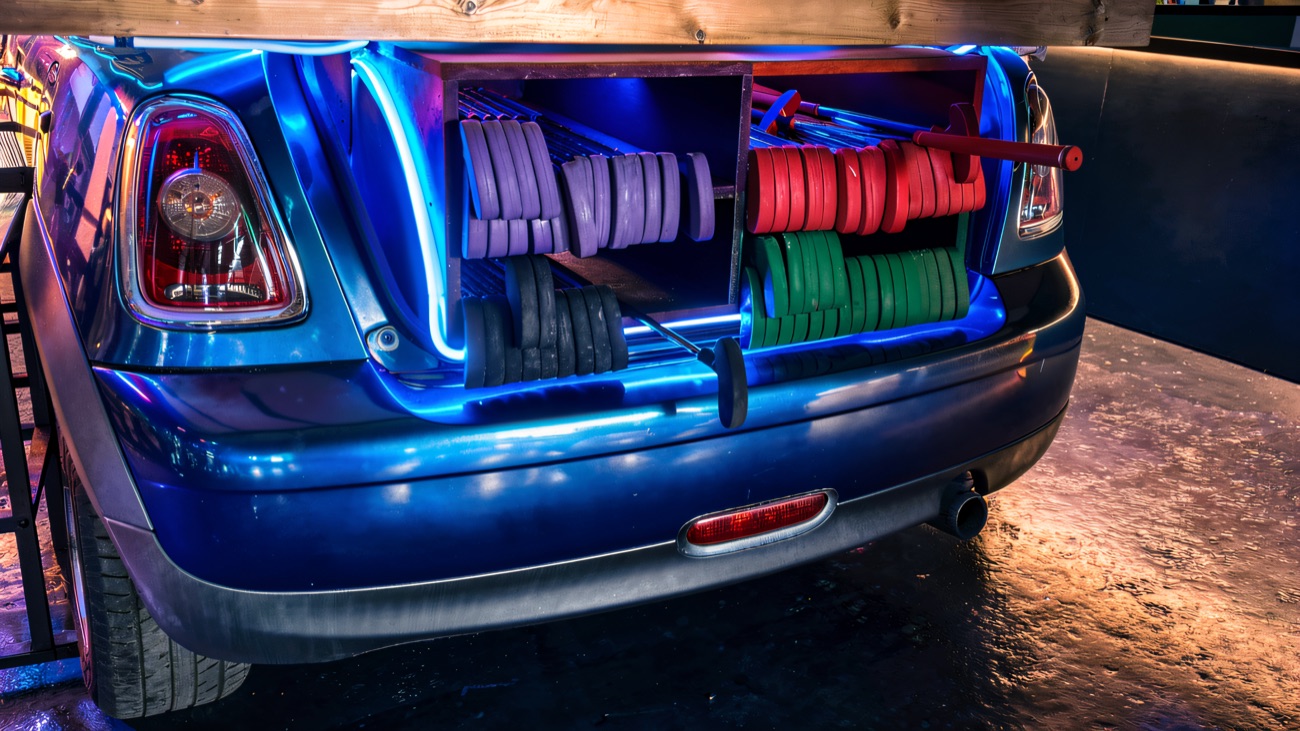 Putters and coloured balls racked in the boot of a car under blue neon