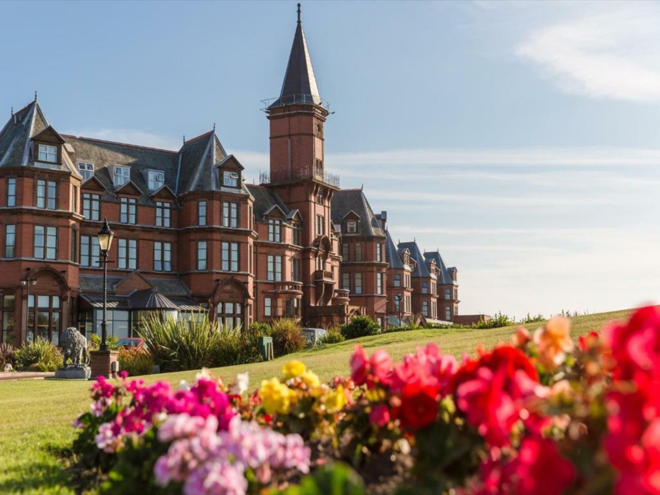 The grand red-brick Victorian hotel above its lawns, with summer flowers in the foreground.