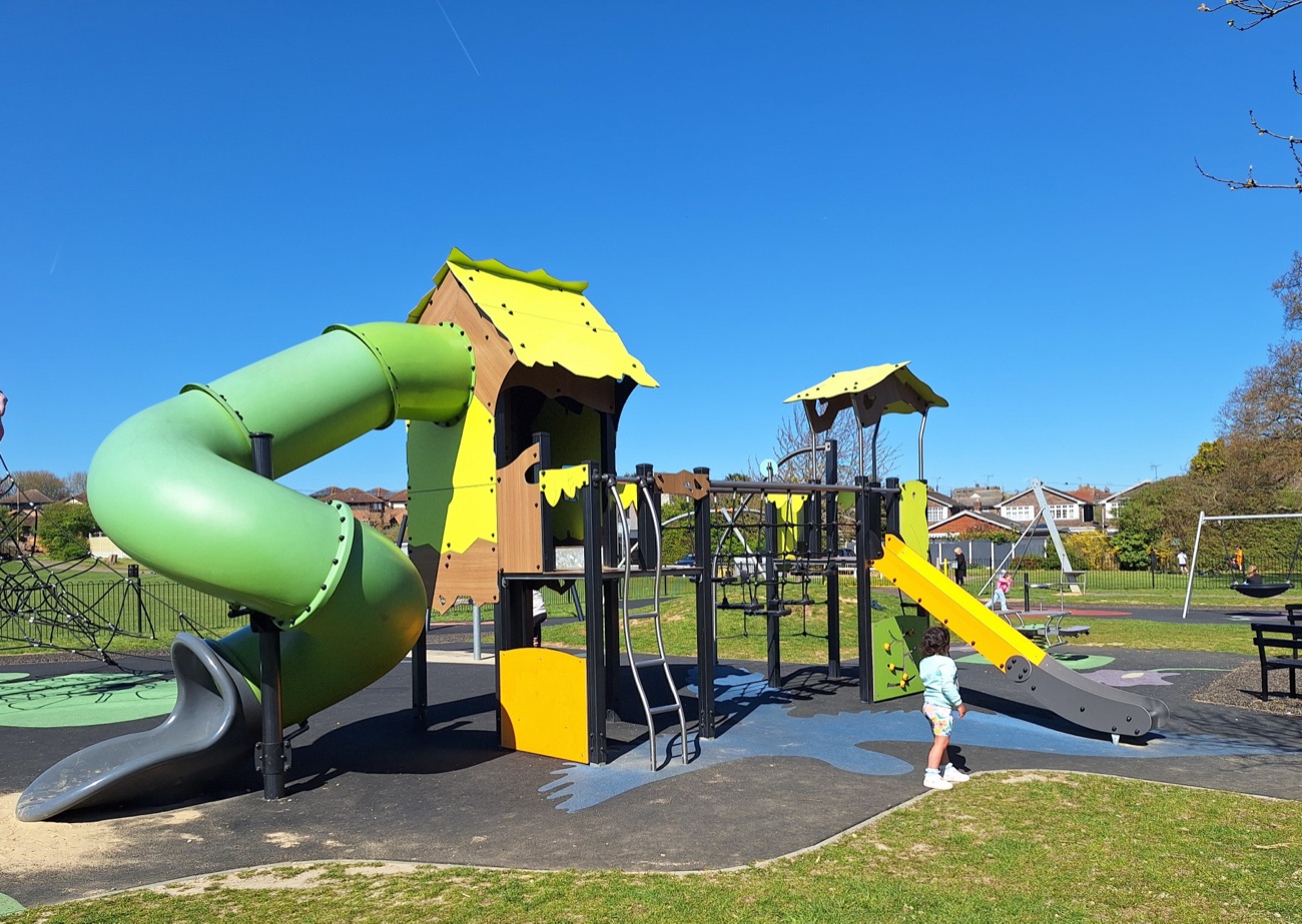 The children's play area at Solitude Park with a green and yellow climbing structure and slides