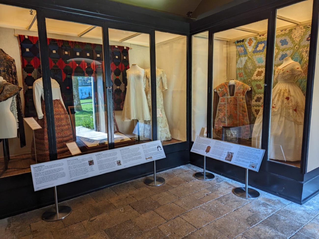 Glass display cases in the costume collection at Springhill, filled with period dresses and quilts