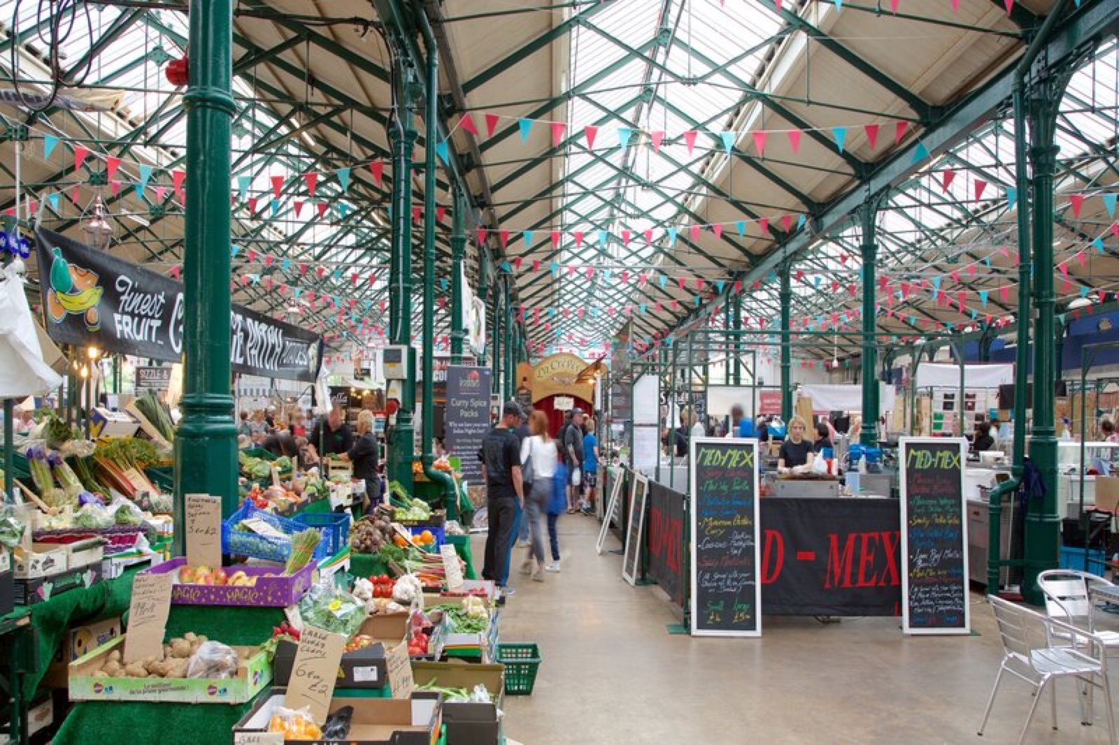 Produce and craft stalls under the iron-and-glass roof with bunting strung overhead at St George's Market