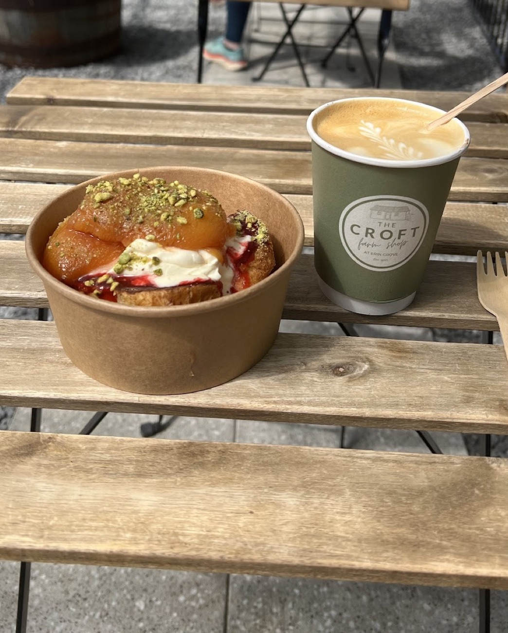 A brunch bowl and a Croft takeaway coffee cup on a scrubbed timber table