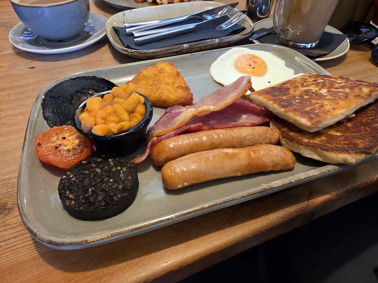 An Ulster fry on a stoneware platter — bacon, sausage, black pudding, egg, soda and potato bread