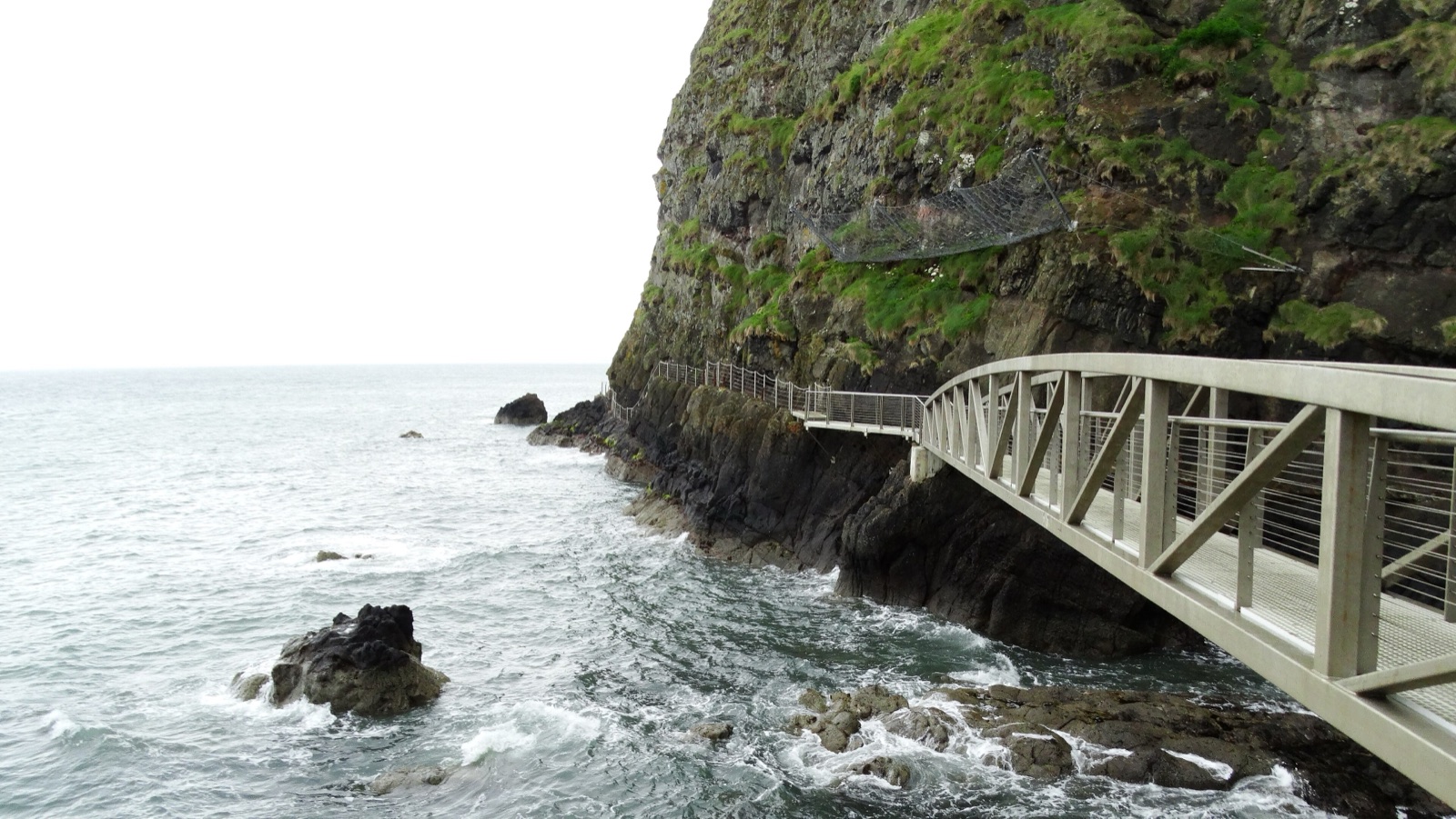 The Gobbins tubular steel footbridge clinging to a sheer sea cliff above crashing waves