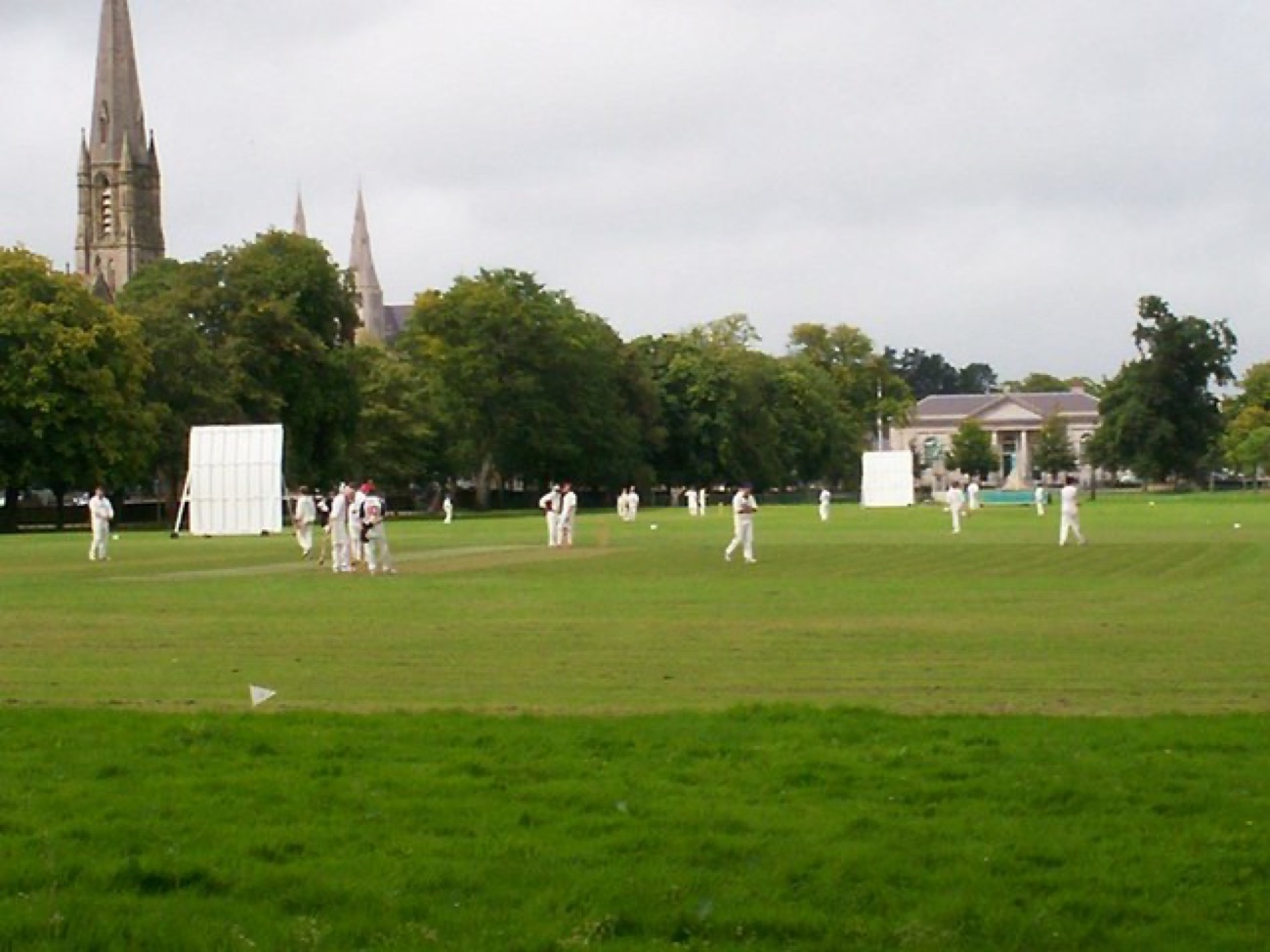 A cricket match on the green at The Mall, Armagh, with cathedral spires behind