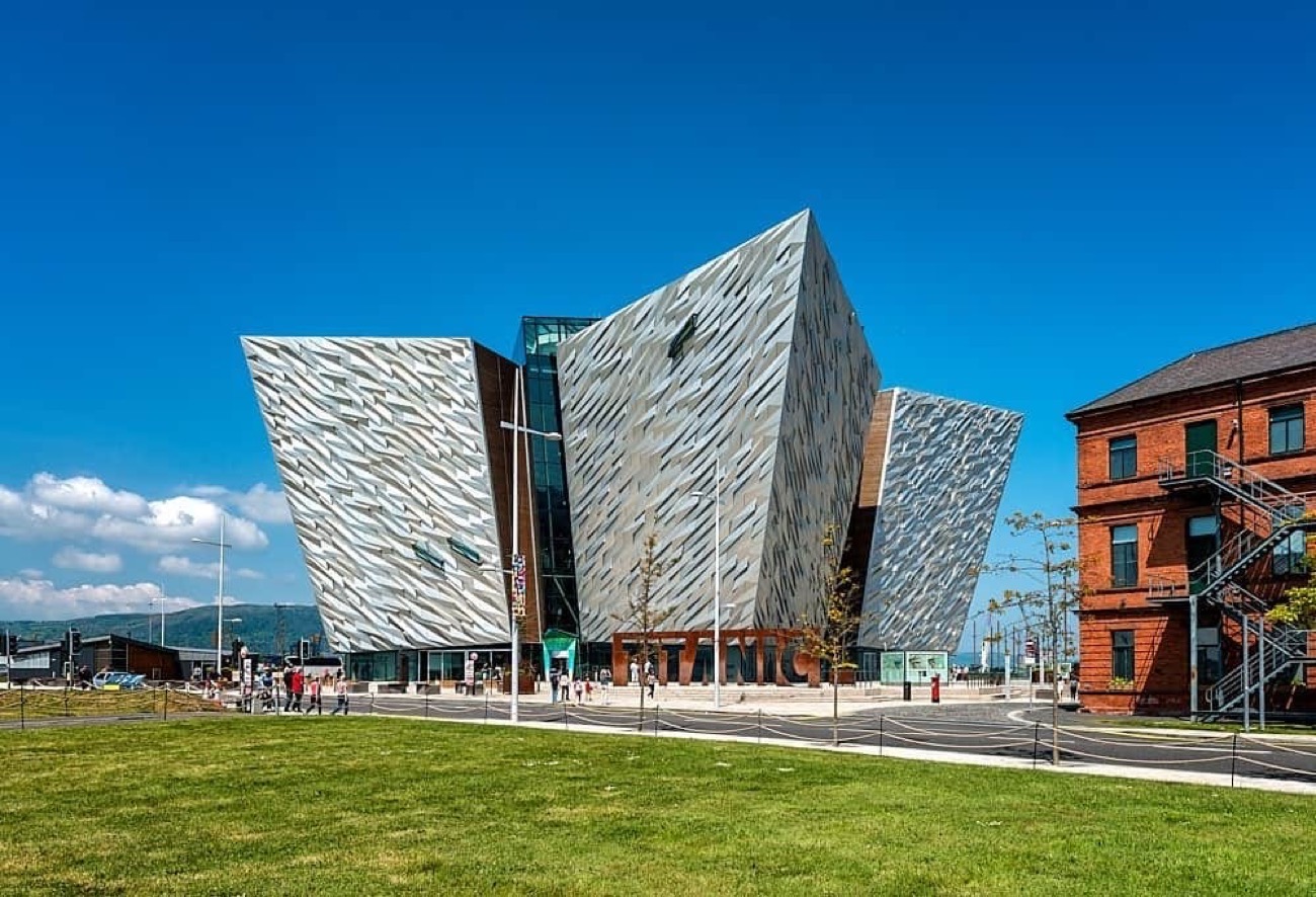 The angular silver building on a bright day beside the lawn