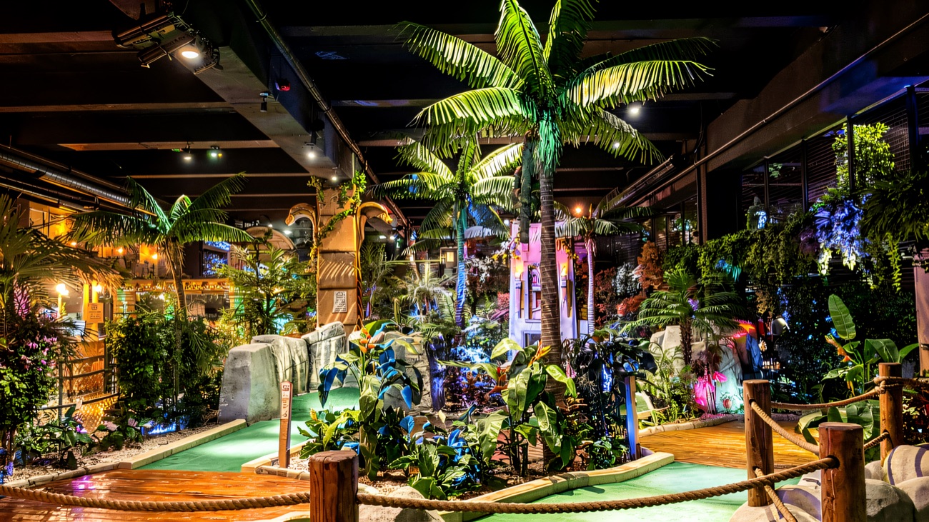 Palm trees and lush foliage tower over the jungle-themed indoor course
