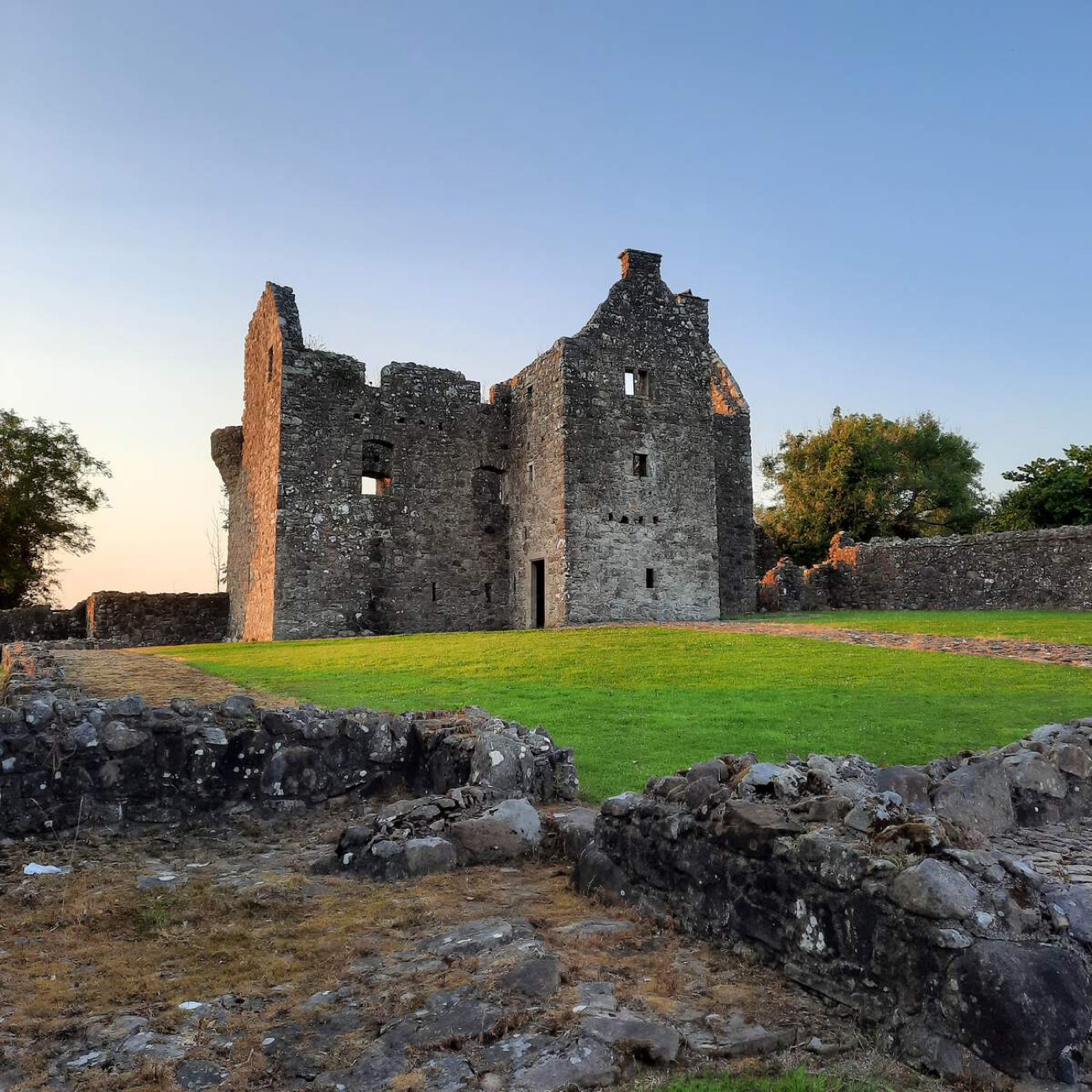 The ruined Tully Castle tower house and bawn walls in the low evening light