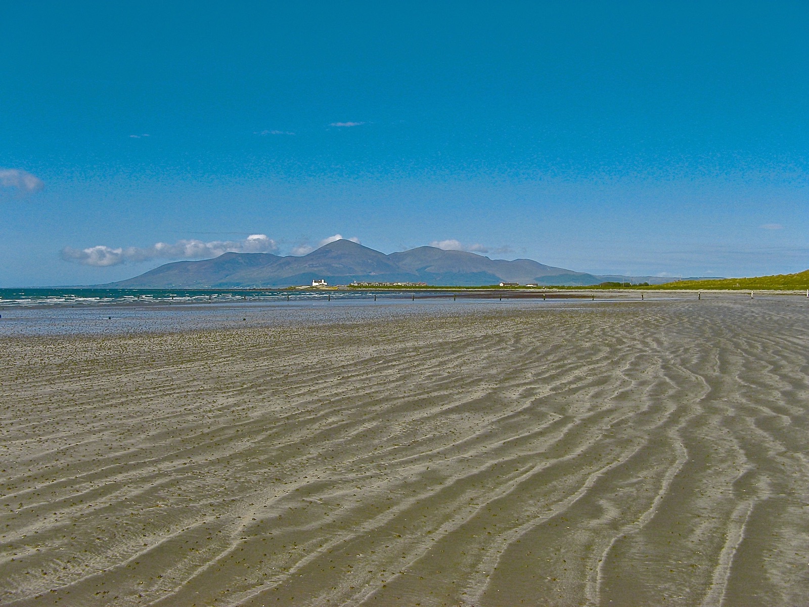 The wide rippled sand at Tyrella Beach at low tide with the Mourne Mountains across Dundrum Bay under a blue summer sky