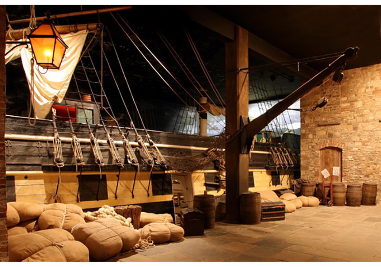 The full-size emigrant sailing ship exhibit indoors, with rigging, barrels and sacks around it