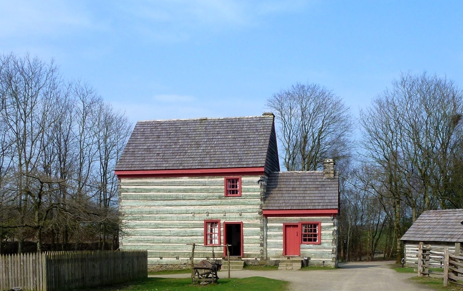 A two-storey timber house with red-painted window frames in the park